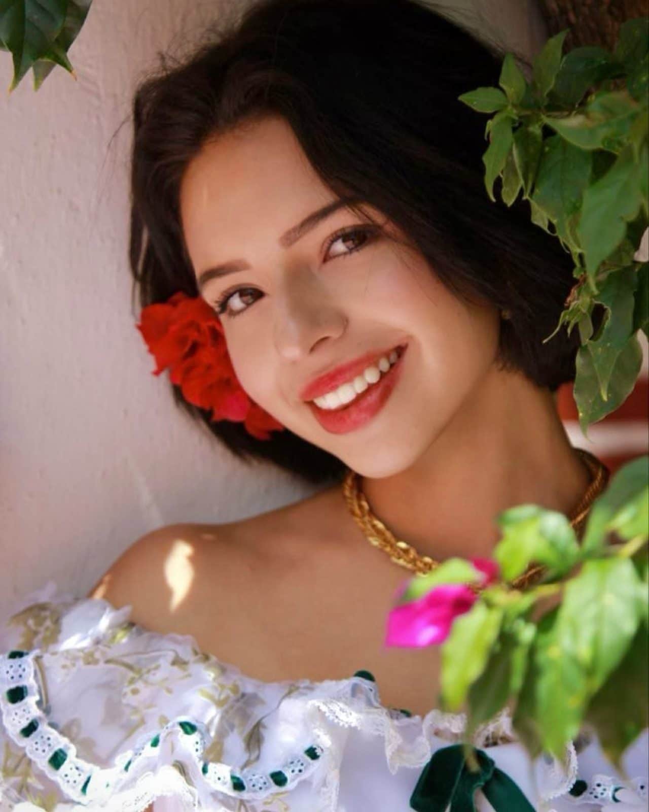 Angela Aguilar con vestido y rosa en la cabeza